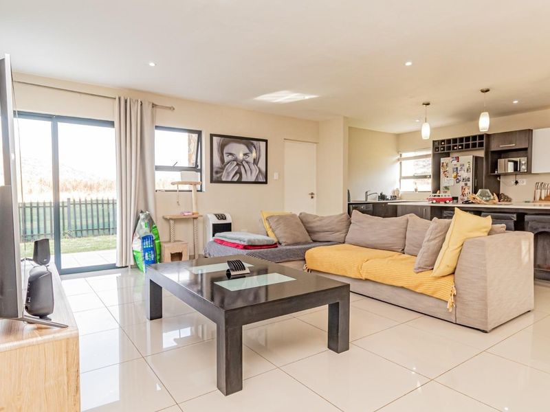 Spacious open-plan living area featuring modern porcelain tiles, recessed lighting, and a contemporary kitchen with a central island and integrated appliances.