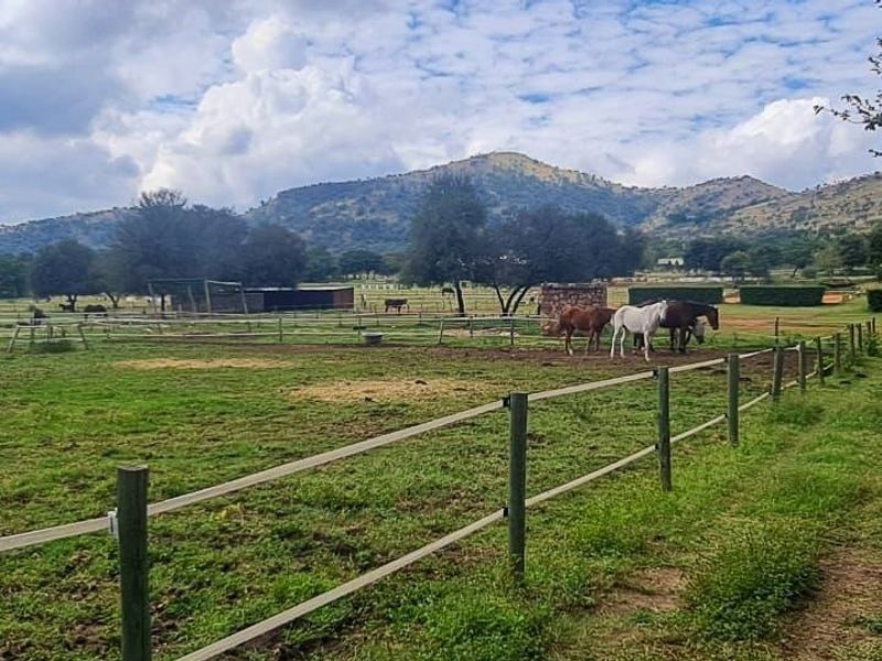 A scenic view of a rural property featuring open pasture land, perimeter fencing, and distant mountain vistas.