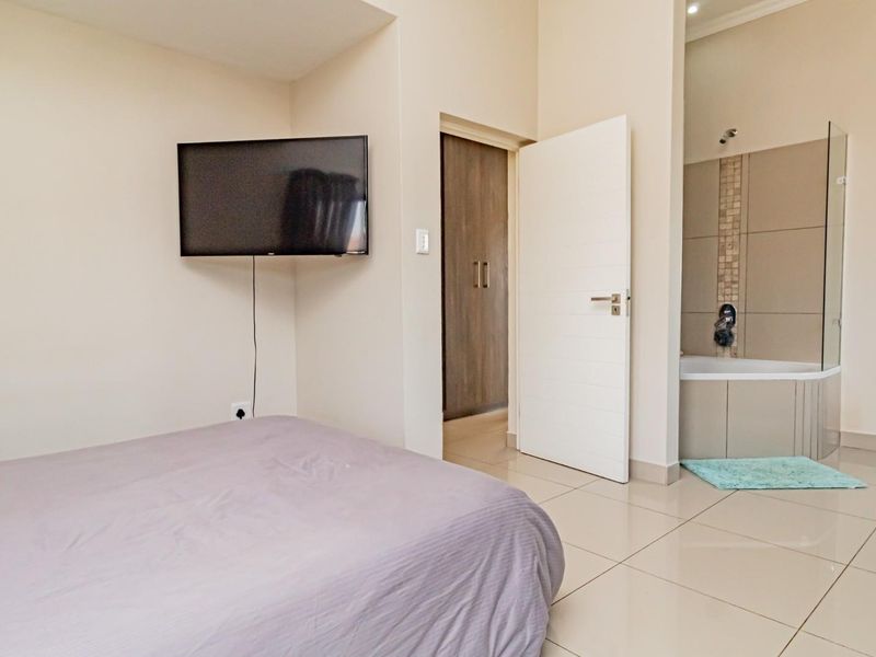 Bedroom featuring tiled flooring, built-in cupboards, and an open-plan en-suite bathroom with a shower, bathtub, and toilet.