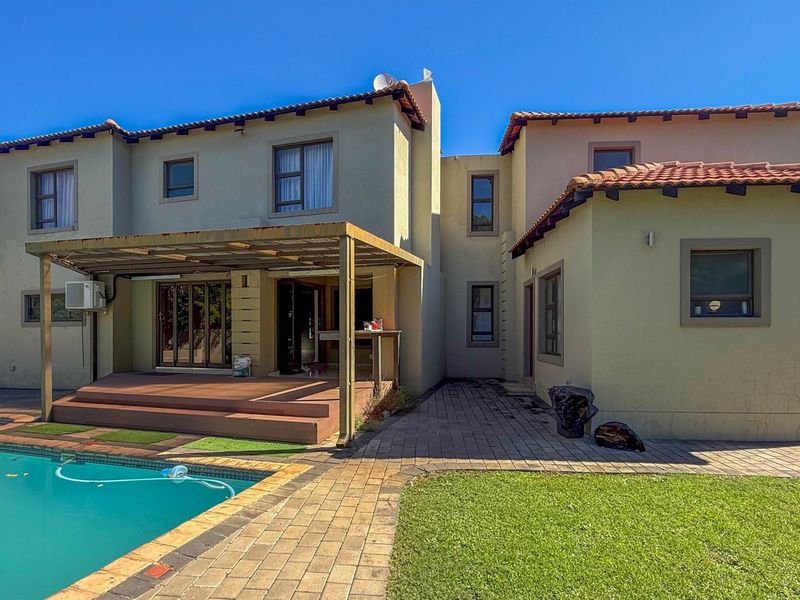 Rear view of the property featuring a swimming pool, paved patio area, timber decking, and a covered outdoor entertainment space.