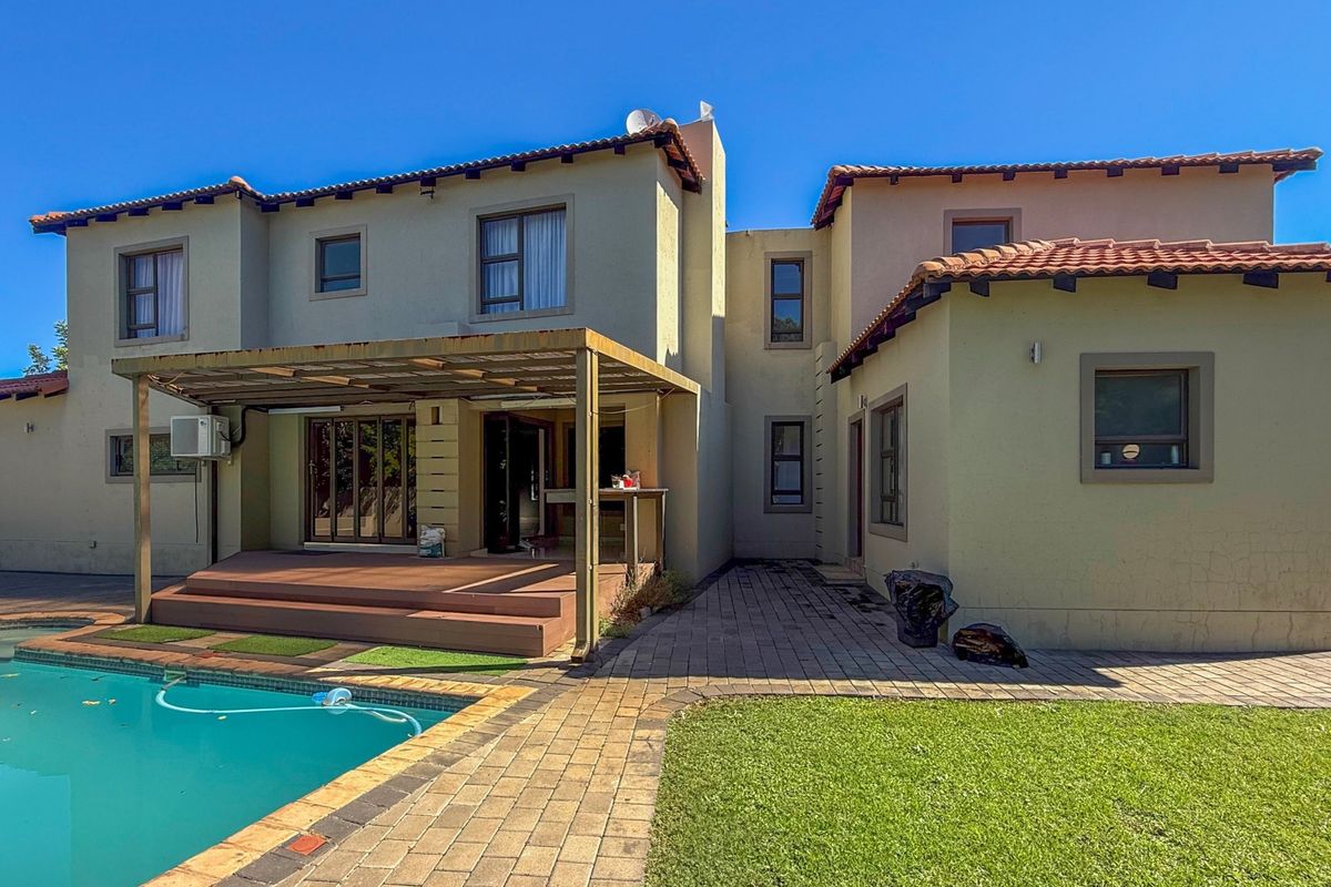 Rear view of the property featuring a swimming pool, paved patio area, timber decking, and a covered outdoor entertainment space.