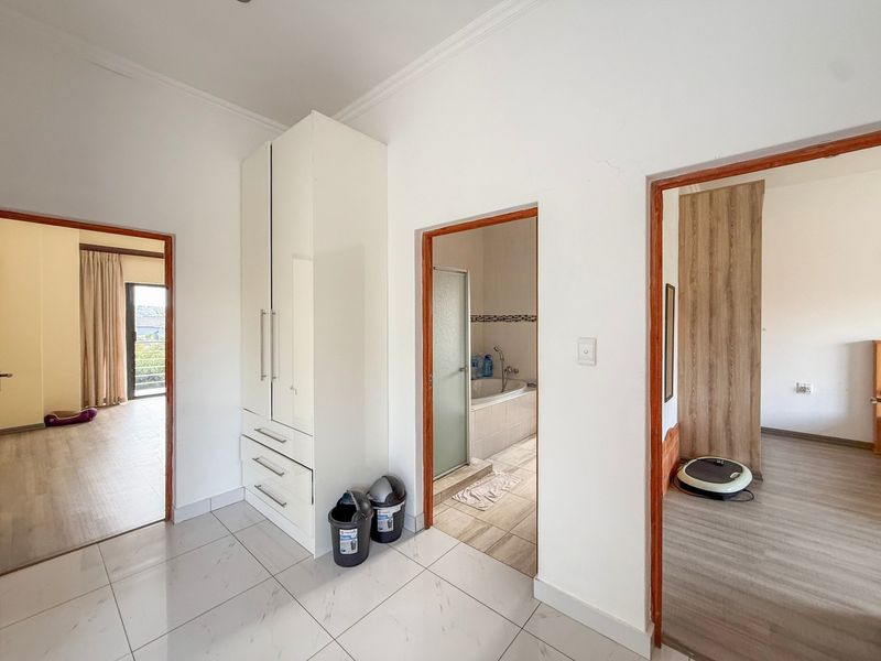 A bright hallway featuring tiled flooring, a built-in cupboard, and access to adjacent rooms including a bathroom.