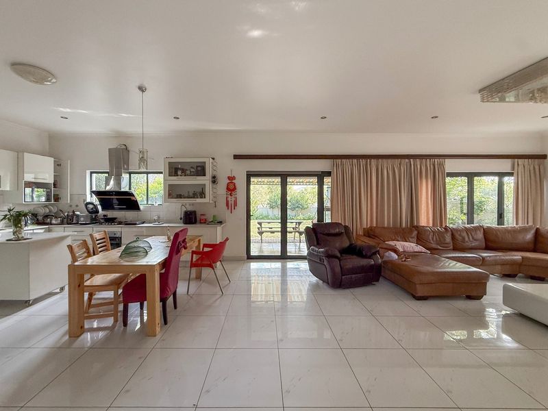 Spacious open-plan living and kitchen area featuring modern tiled flooring, sleek cabinetry, and large sliding doors providing seamless access to the rear garden.