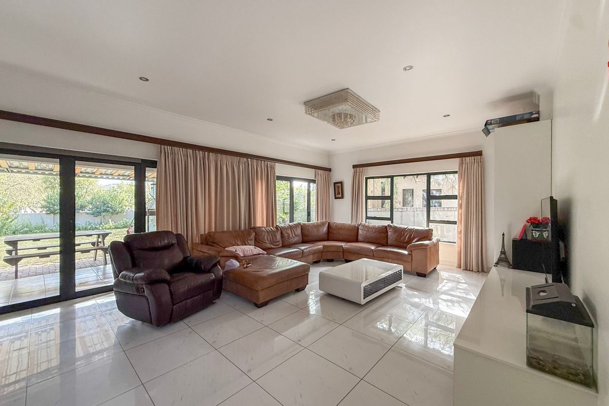 Spacious living room featuring large windows, sliding glass doors leading to the patio, and polished tiled flooring with recessed lighting.