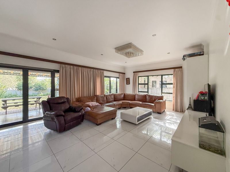 Spacious living room featuring large windows, sliding glass doors leading to the patio, and polished tiled flooring with recessed lighting.