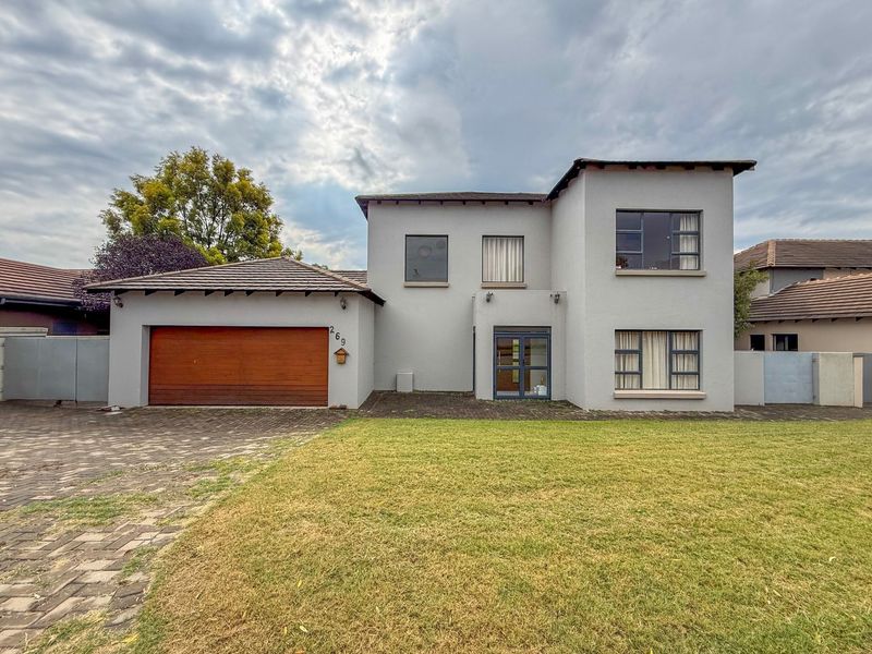 A well-maintained two-story residential property featuring a paved driveway, integrated double garage, and a spacious front lawn.