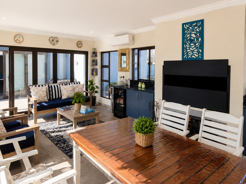 Spacious open-plan living and dining area featuring a built-in fireplace, kitchenette with sink, and large sliding doors opening to the outdoor patio.