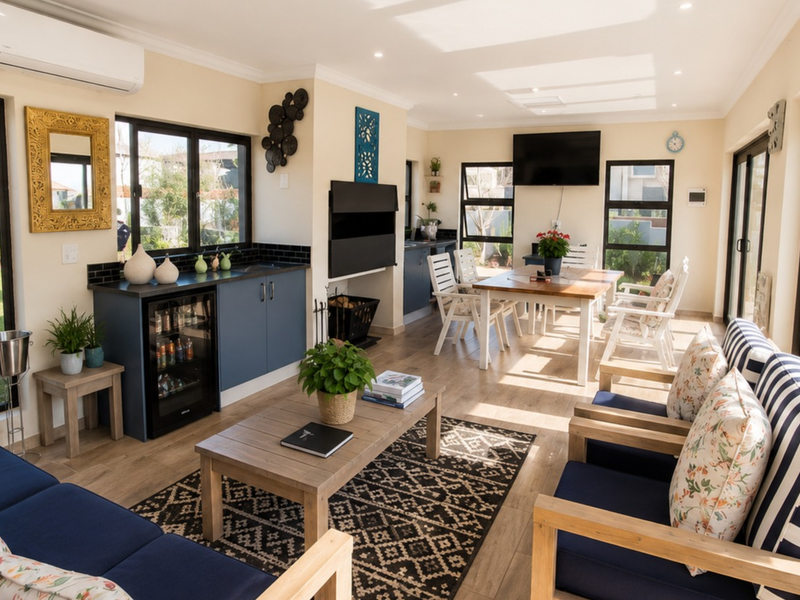 Bright open-plan living and dining area featuring wood-look flooring, built-in cabinetry with a beverage fridge, and large sliding doors opening to the garden.