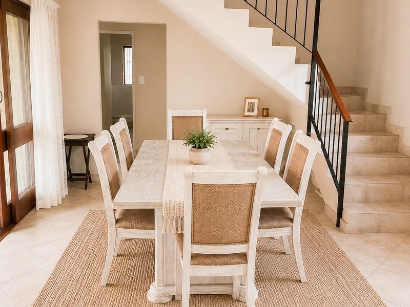 A bright dining area featuring tiled flooring, a staircase with metal railings, and a sliding glass door providing access to the patio.