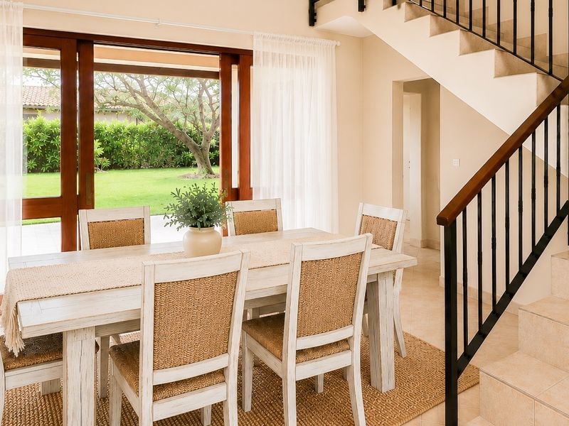 Bright dining area featuring a tiled staircase with wrought iron balustrade and large wooden sliding doors opening to a landscaped garden.