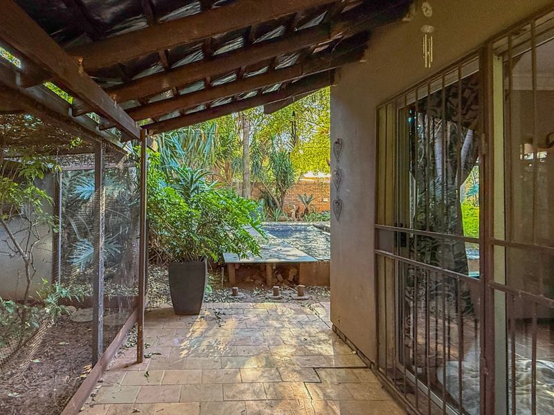 Covered patio area featuring tiled flooring and a timber pergola, providing direct access to the garden and swimming pool area.