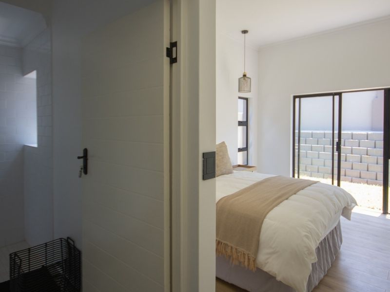 A bright bedroom featuring modern sliding glass doors leading to an outdoor area, adjacent to a clean, tiled bathroom space.