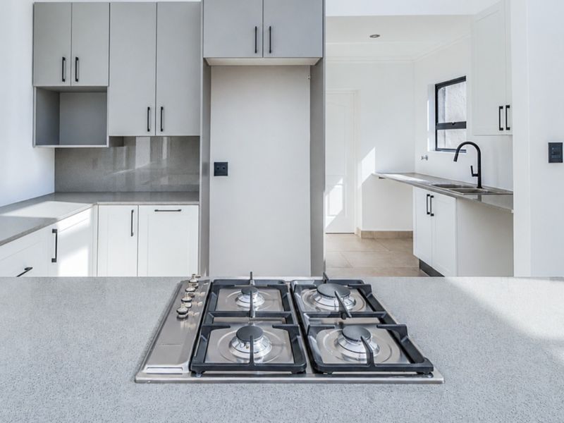 Modern kitchen featuring a central gas hob, stone countertops, sleek cabinetry, and a secondary prep area with a sink.