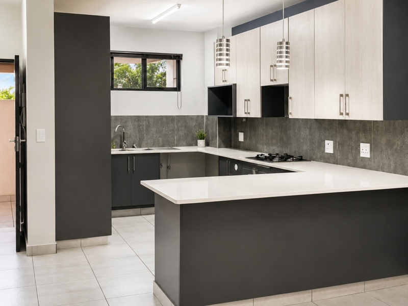 Modern kitchen featuring two-tone cabinetry, stone countertops, a gas hob, and tiled flooring, offering a clean and functional workspace.