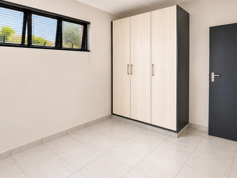 A bright, modern bedroom featuring neutral tiled flooring, a built-in wardrobe, and a window with fitted blinds.