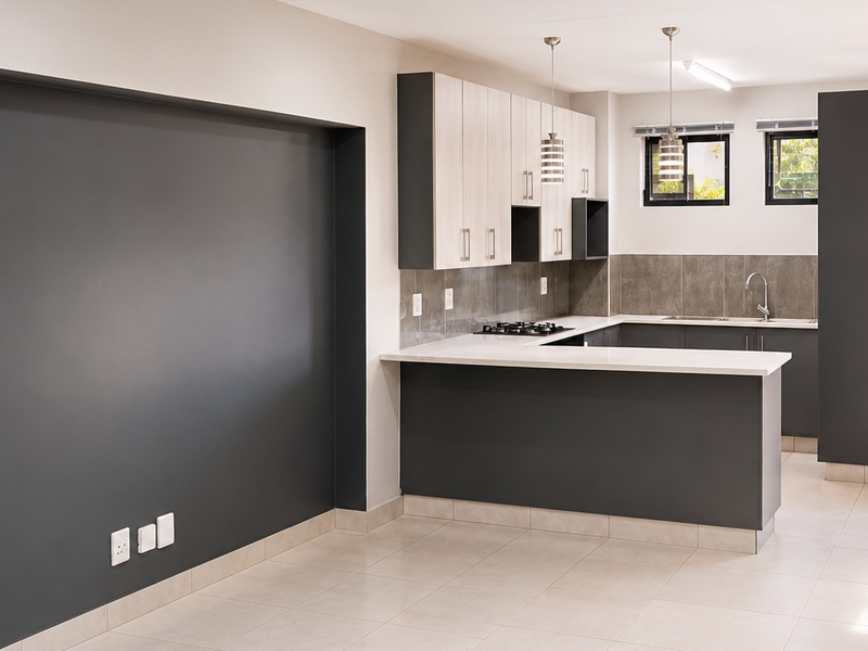 Modern open-plan kitchen featuring sleek two-tone cabinetry, stone countertops, a gas hob, and contemporary pendant lighting in a clean, well-maintained space.