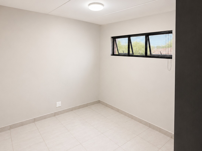 A clean, empty bedroom featuring neutral tiled flooring, a top-hung window with fitted blinds, and a modern ceiling light fixture.