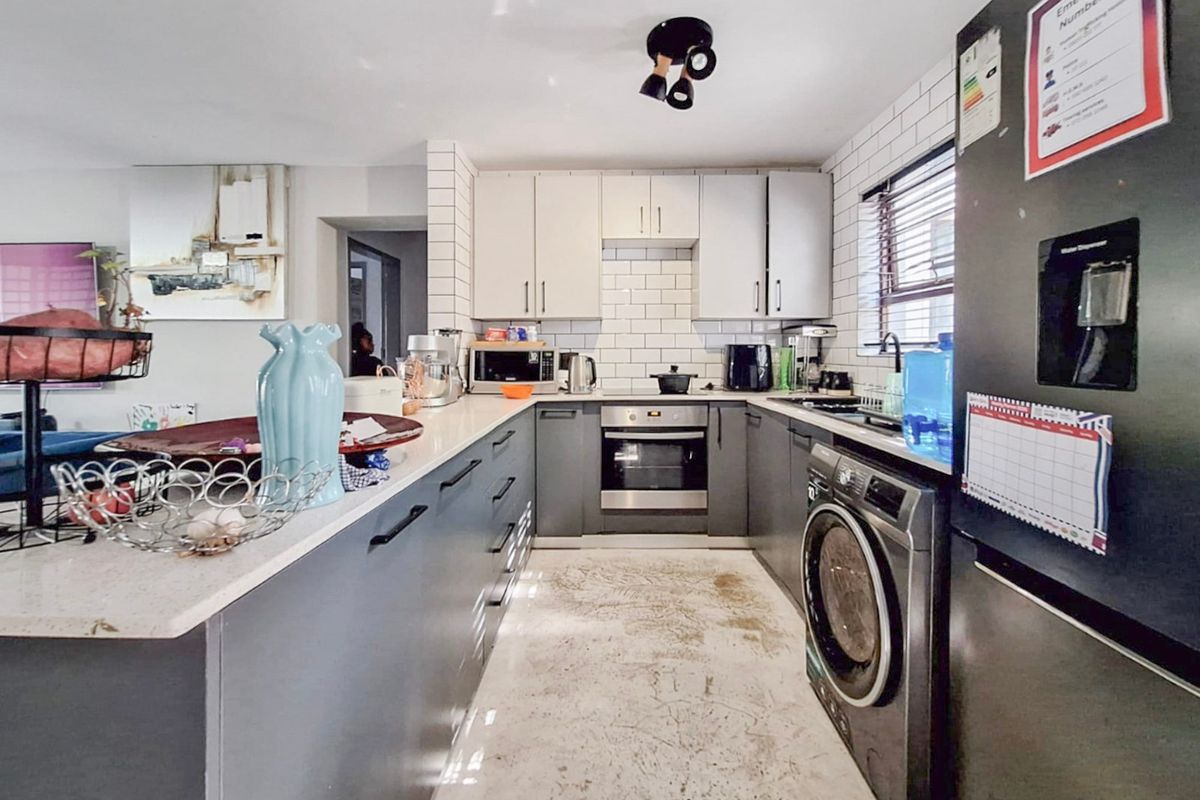 Modern kitchen featuring two-tone cabinetry, stone countertops, subway tile backsplash, and integrated appliances, offering a functional layout for daily cooking and preparation.