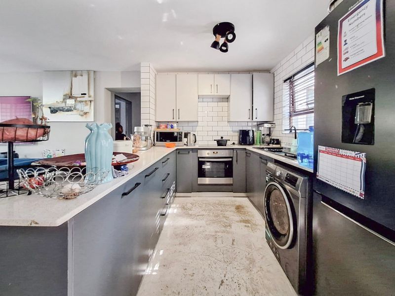 Modern kitchen featuring two-tone cabinetry, stone countertops, subway tile backsplash, and integrated appliances, offering a functional layout for daily cooking and preparation.