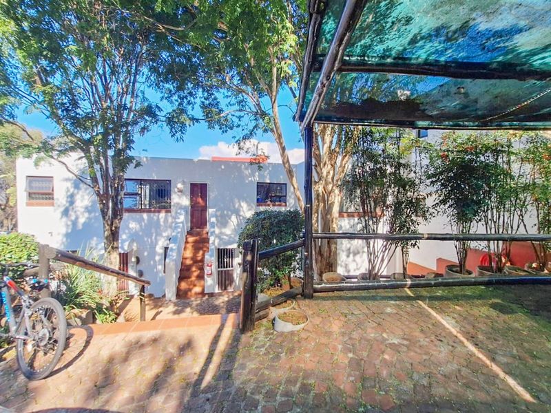 Rear exterior view of the apartment featuring a paved patio area with a shade cloth pergola and an external staircase leading to the entrance.