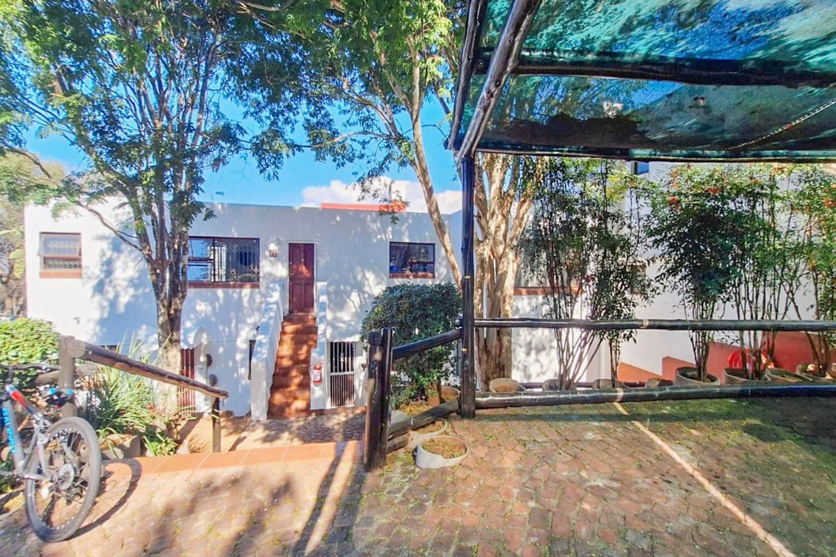 Rear exterior view of the apartment featuring a paved patio area with a shade cloth pergola and an external staircase leading to the entrance.