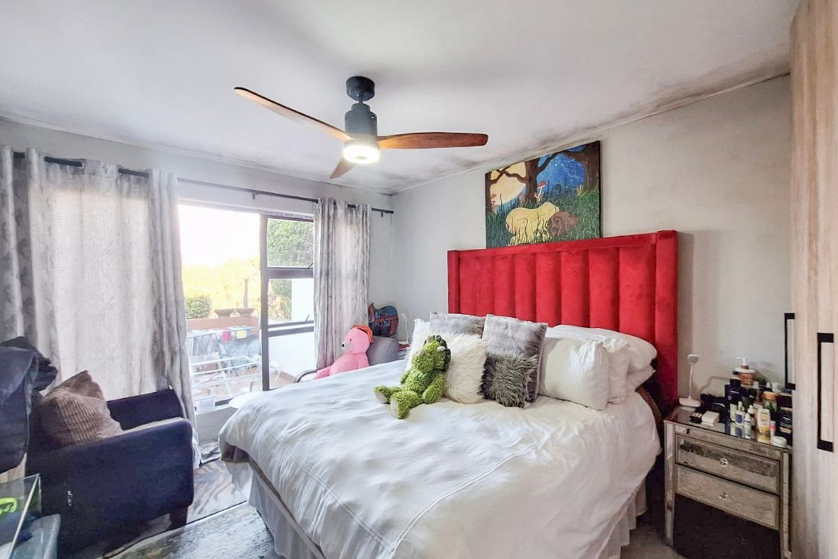 A bedroom featuring a ceiling fan, built-in wardrobe, and sliding glass door access to an outdoor area, showing signs of ceiling water damage.