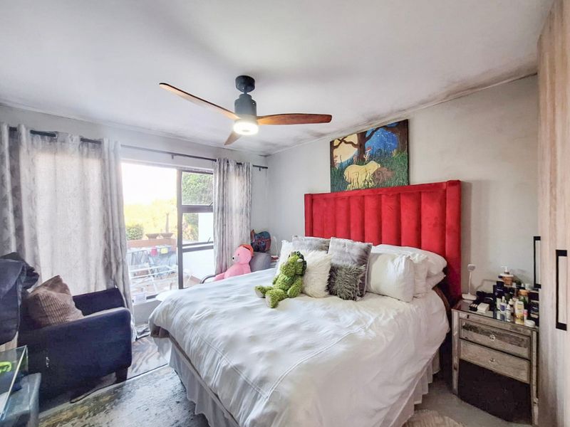 A bedroom featuring a ceiling fan, built-in wardrobe, and sliding glass door access to an outdoor area, showing signs of ceiling water damage.