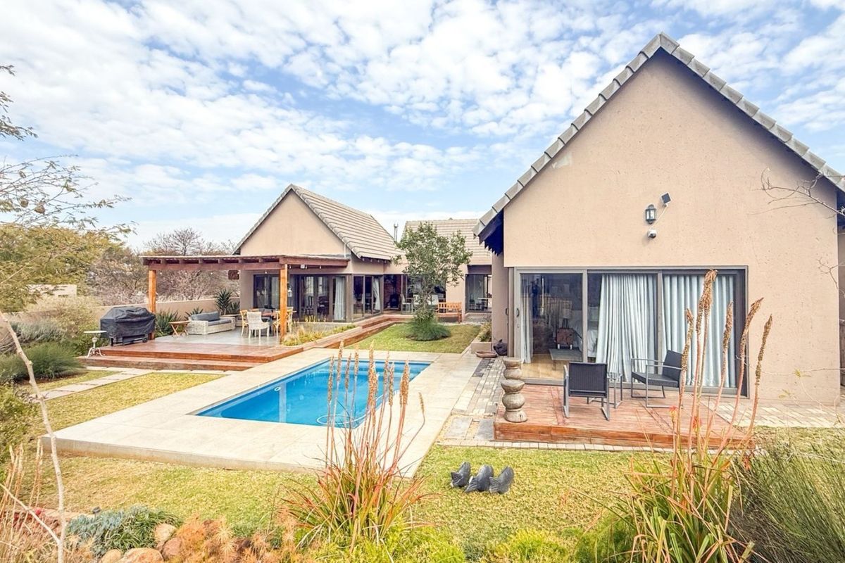 Rear exterior view featuring a swimming pool, timber decking, a covered pergola, and sliding glass doors leading into the residence.