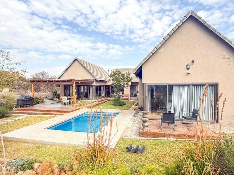 Rear exterior view featuring a swimming pool, timber decking, a covered pergola, and sliding glass doors leading into the residence.
