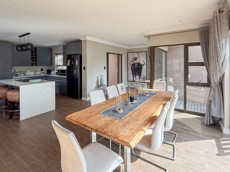 Spacious open-plan living and dining area featuring a modern kitchen with a central island, sleek cabinetry, and large sliding doors leading to the outdoors.