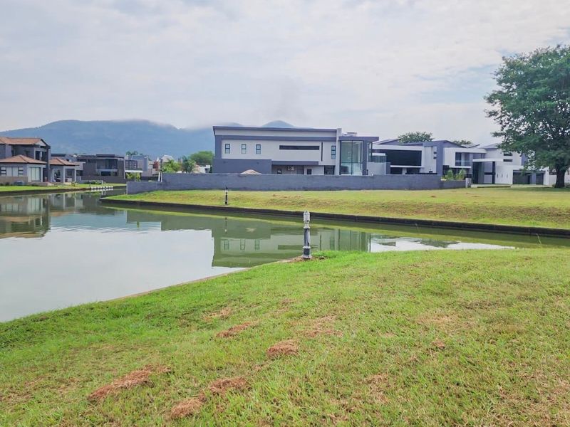 A scenic view of a residential canal and landscaped lawn area, showcasing the waterfront setting of the property.