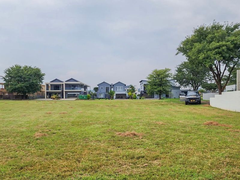 A spacious, level residential vacant plot featuring a well-maintained grass lawn, situated within an established neighborhood with surrounding modern homes.