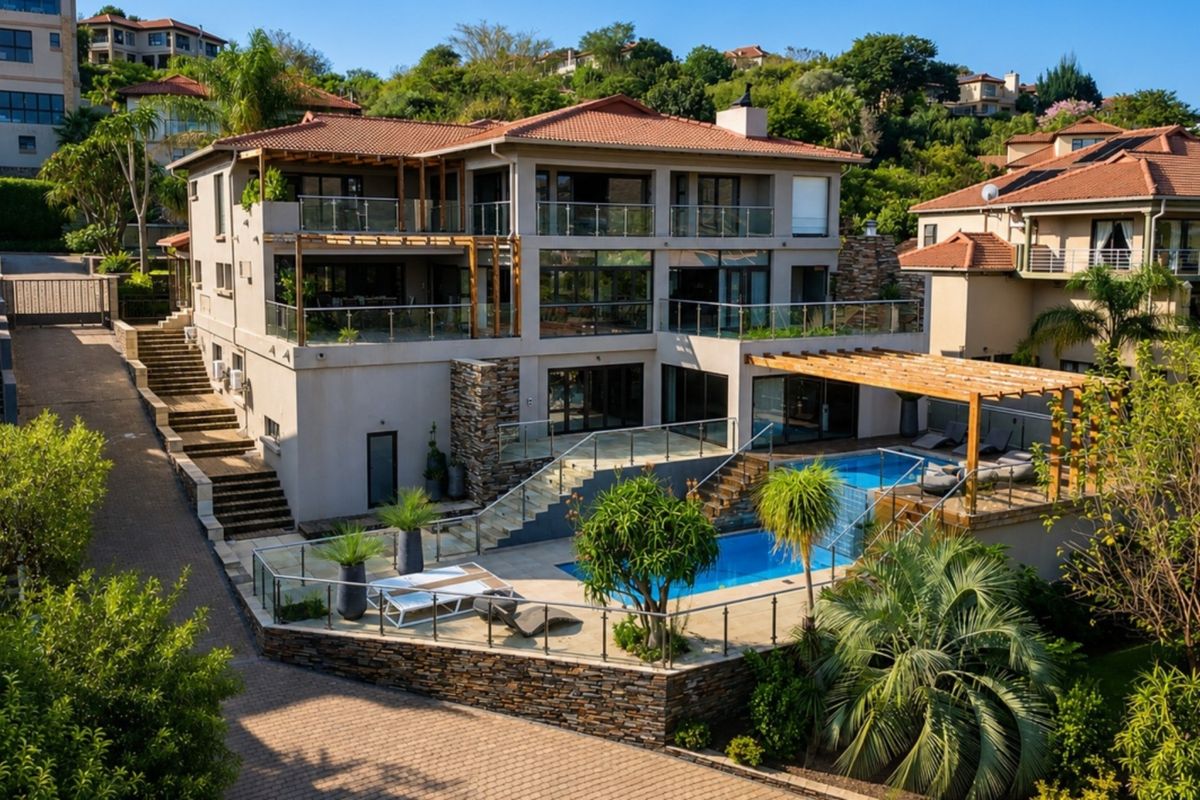 A multi-level rear exterior view featuring a swimming pool, glass balustrades, timber pergolas, and stone-clad retaining walls in a well-maintained residential setting.