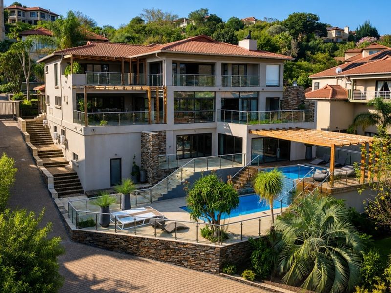 A multi-level rear exterior view featuring a swimming pool, glass balustrades, timber pergolas, and stone-clad retaining walls in a well-maintained residential setting.