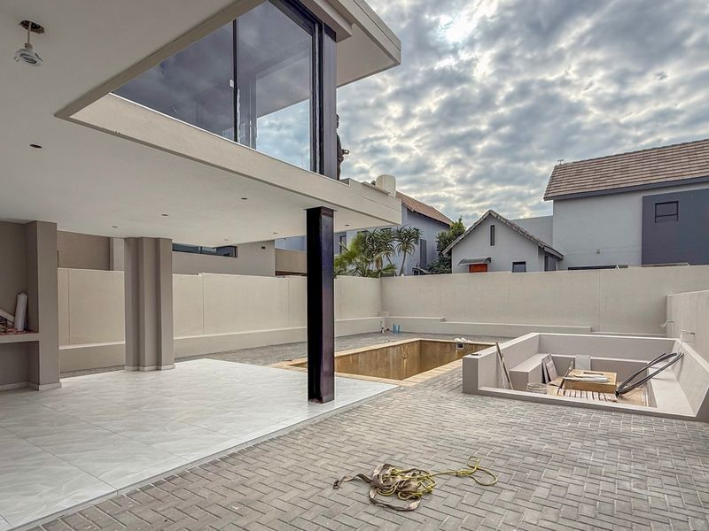 Outdoor entertainment area featuring a swimming pool, tiled patio, and built-in braai, currently in a state of completion with construction finishes pending.