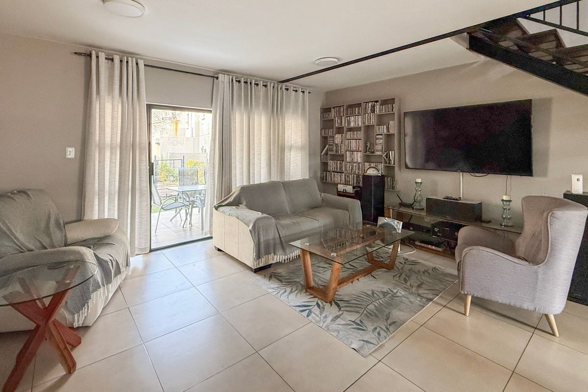A bright living room featuring tiled flooring, a built-in shelving unit, and a sliding glass door providing access to the outdoor patio area.