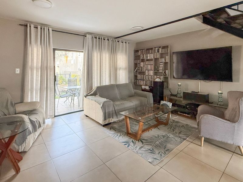 A bright living room featuring tiled flooring, a built-in shelving unit, and a sliding glass door providing access to the outdoor patio area.