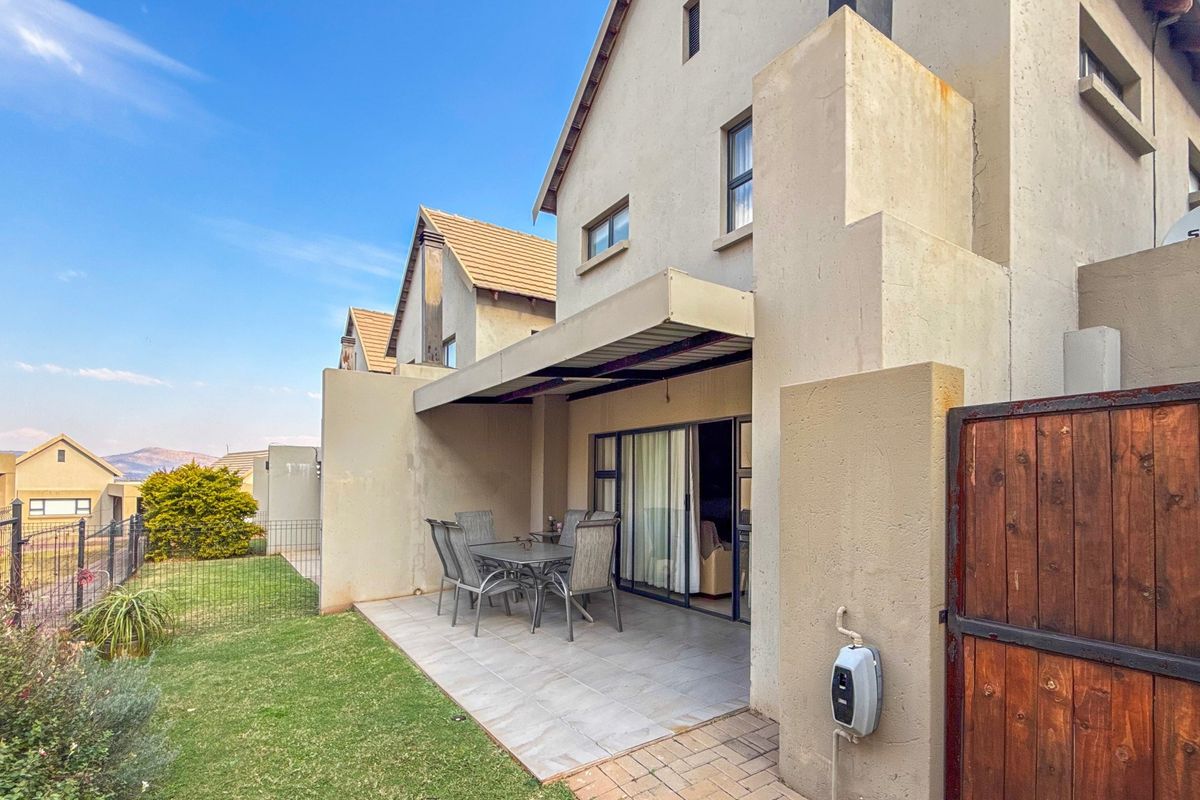 Rear view of the townhouse featuring a tiled patio area, sliding door access, and a small private garden space.