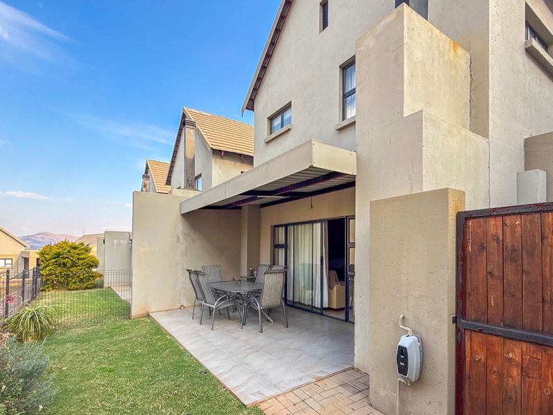 Rear view of the townhouse featuring a tiled patio area, sliding door access, and a small private garden space.