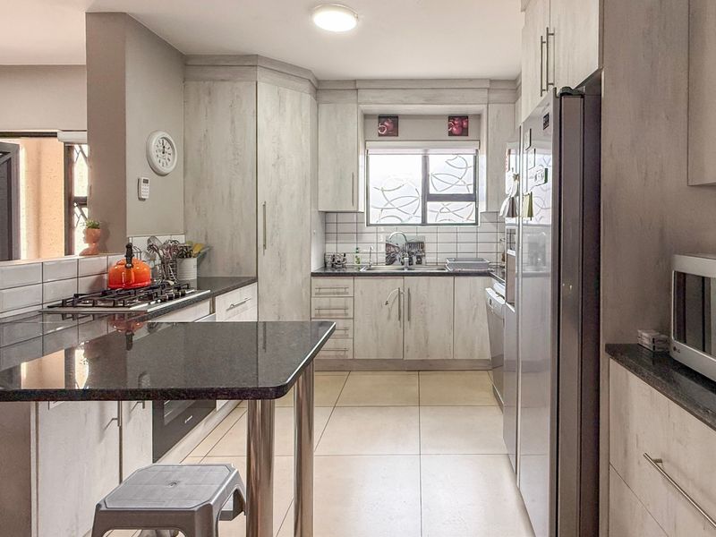 A functional kitchen featuring light-toned cabinetry, granite countertops, a gas hob, and a breakfast nook, providing a practical workspace for daily cooking.