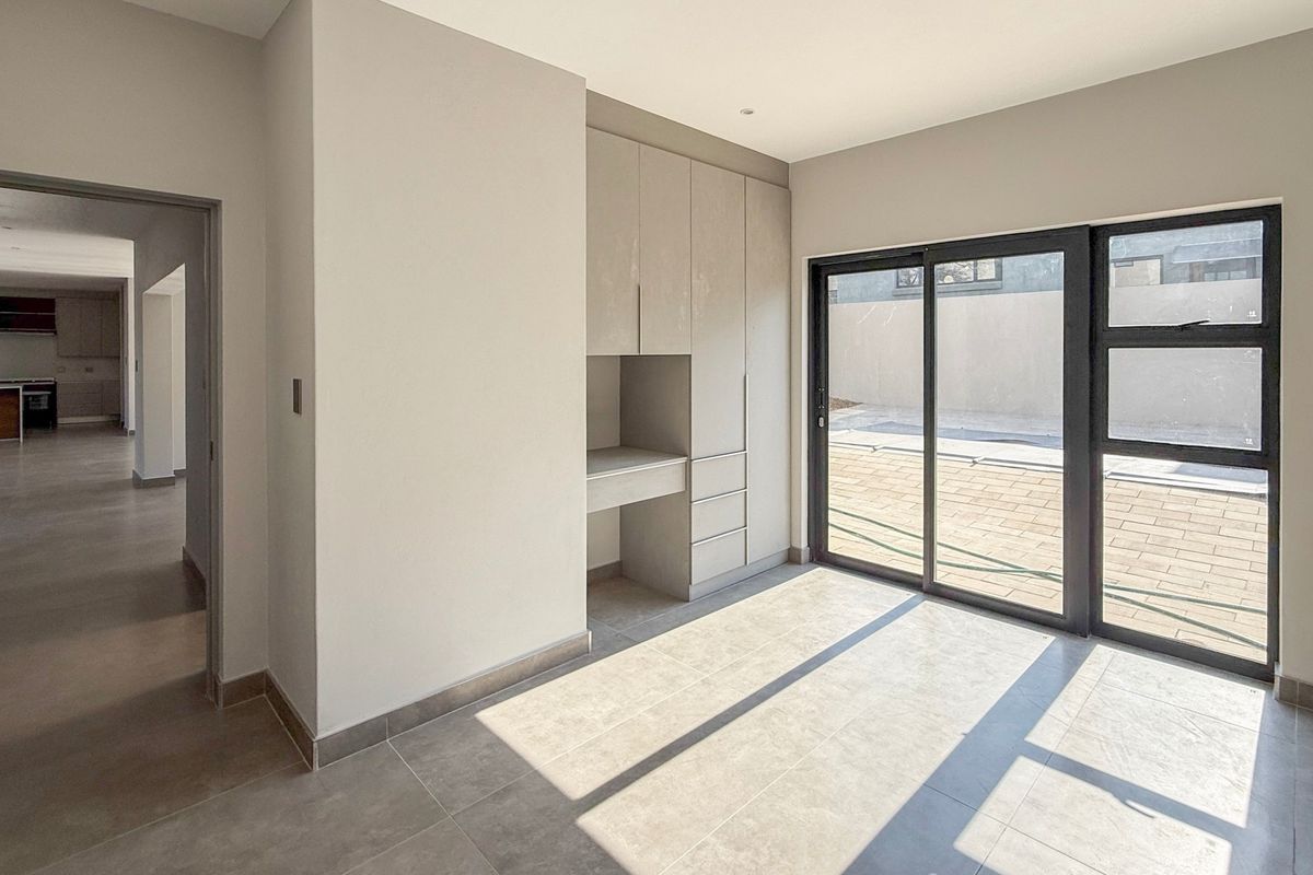 A bright, modern living space featuring neutral tiled floors, built-in cabinetry, and large sliding glass doors providing access to the outdoor patio area.