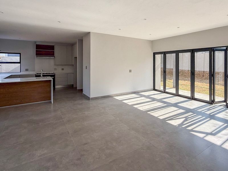 Spacious open-plan living and kitchen area featuring modern cabinetry, stone countertops, gas hob, and large bi-fold doors opening to the rear garden.