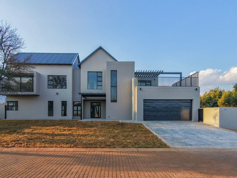 Modern double-story residential property featuring a contemporary facade, metal roofing, integrated double garage, and an upper-level balcony with pergola.