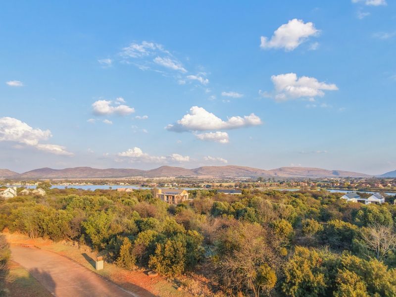An elevated aerial view showcasing the surrounding natural landscape, distant mountains, and local residential estate infrastructure.