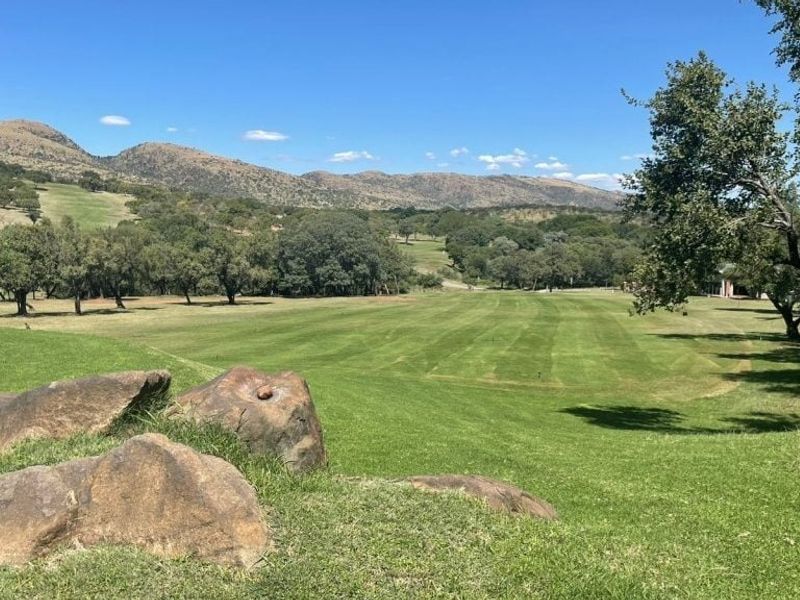 A scenic view overlooking a well-maintained golf course with rolling hills and mature trees in the background.