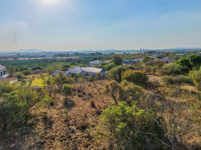 An aerial view of a residential property featuring natural landscape and surrounding neighborhood structures.
