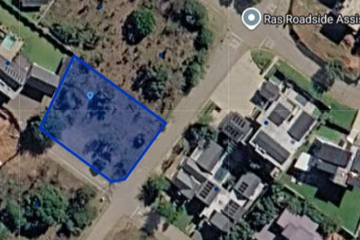 An aerial view of a vacant residential land plot situated within a developed neighborhood.