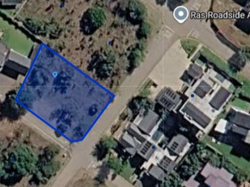 An aerial view of a vacant residential land plot situated within a developed neighborhood.