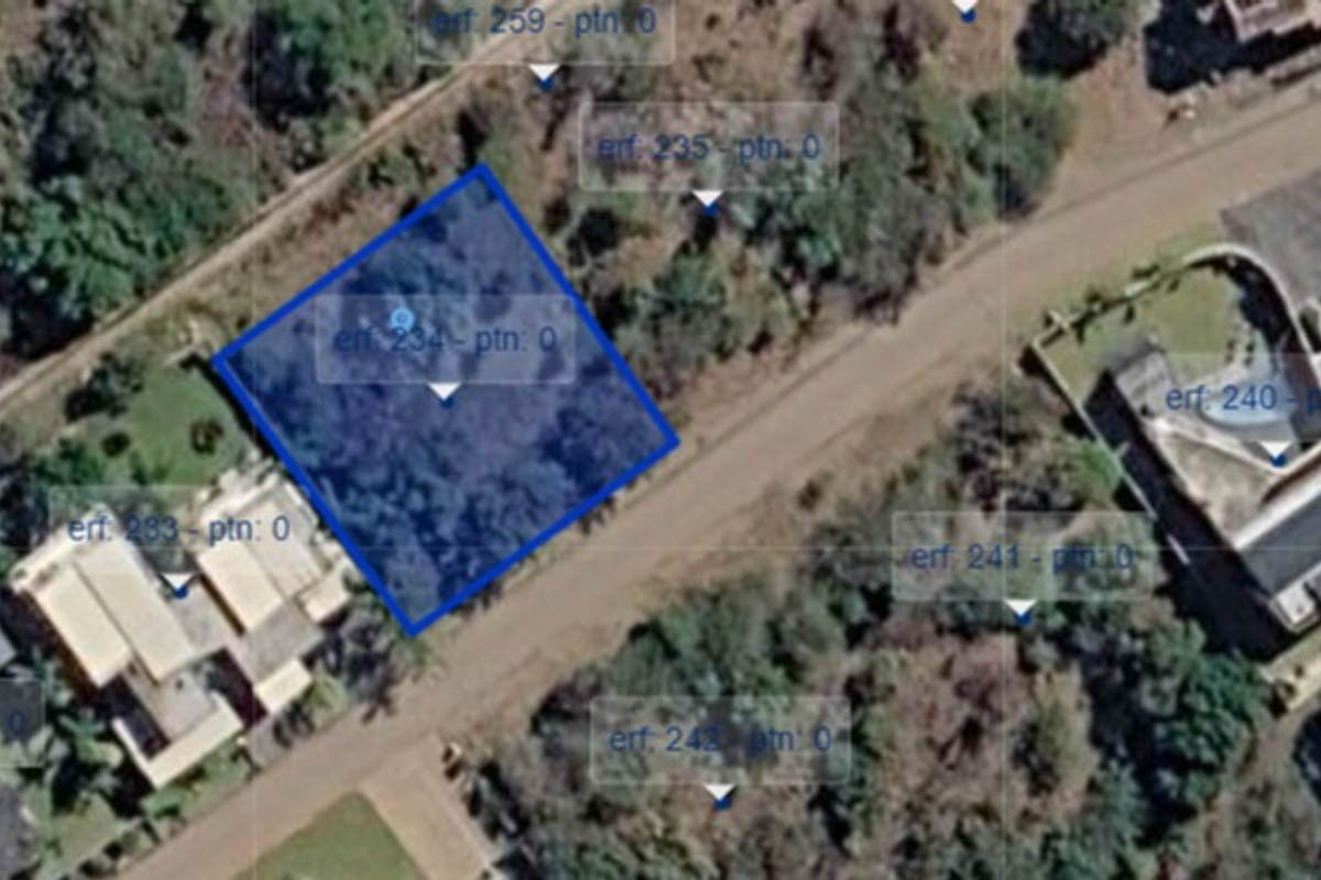 An aerial view of a vacant residential land plot, highlighted in blue, situated within a developed neighborhood.