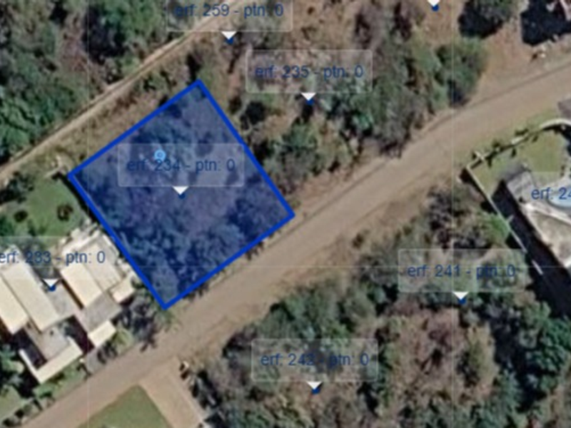 An aerial view of a vacant residential land plot, highlighted in blue, situated within a developed neighborhood.